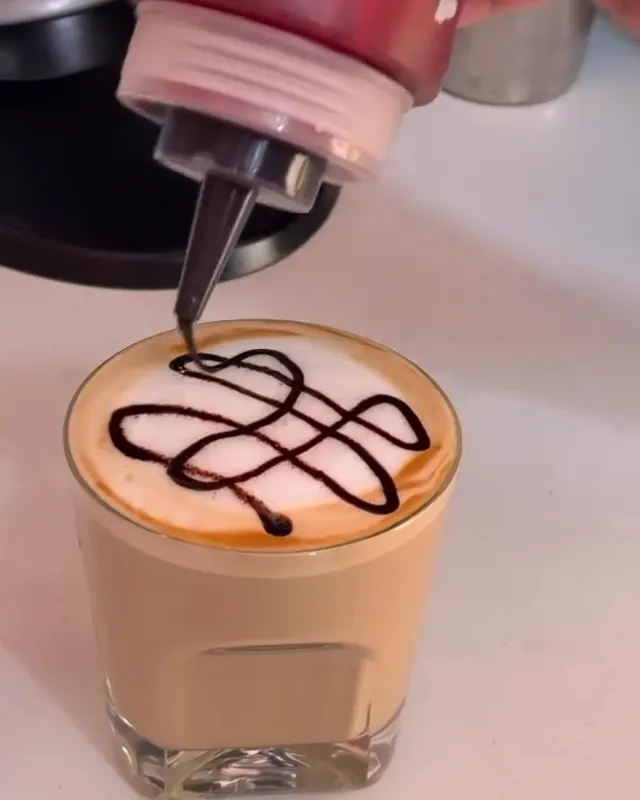 A glass of coffee finished with a chocolate drizzle