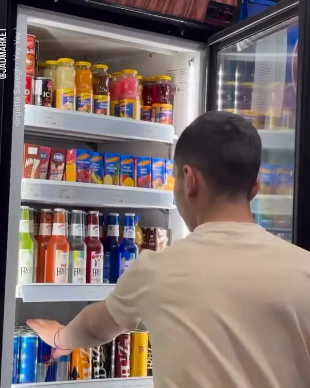 Reaching into a fridge full of bottled drinks